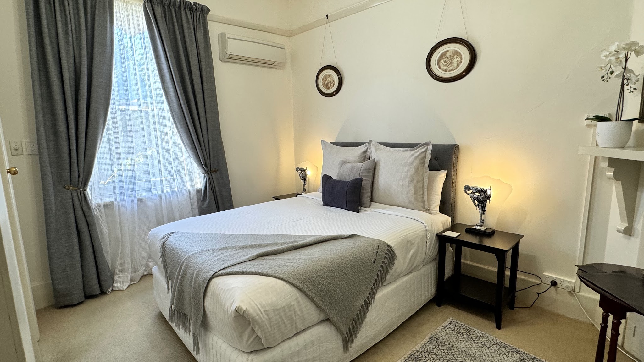 A second guest bedroom at Barossa House with grey drapes, a lace curtain and framed prints