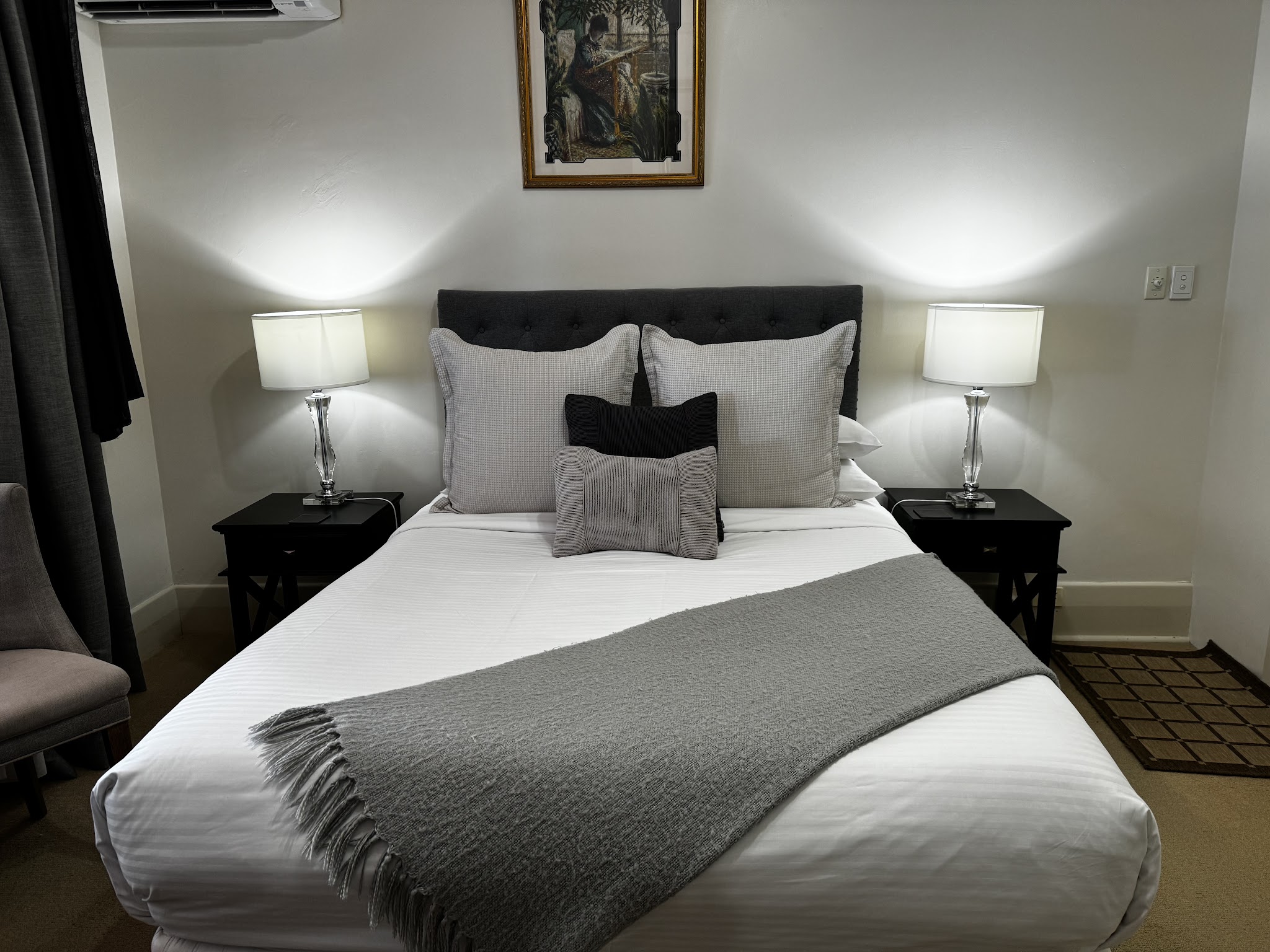 A guest bedroom at Barossa House with a queen bed, buttoned headboard and a pair of lamps