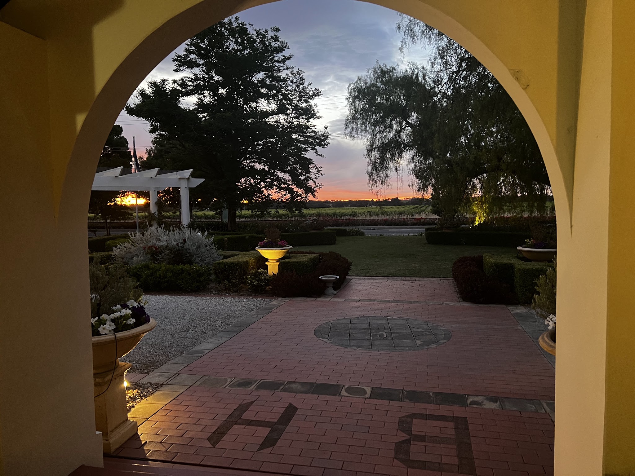 Looking out through the entrance arch at Barossa House at dusk, over the lit garden towards the vineyards