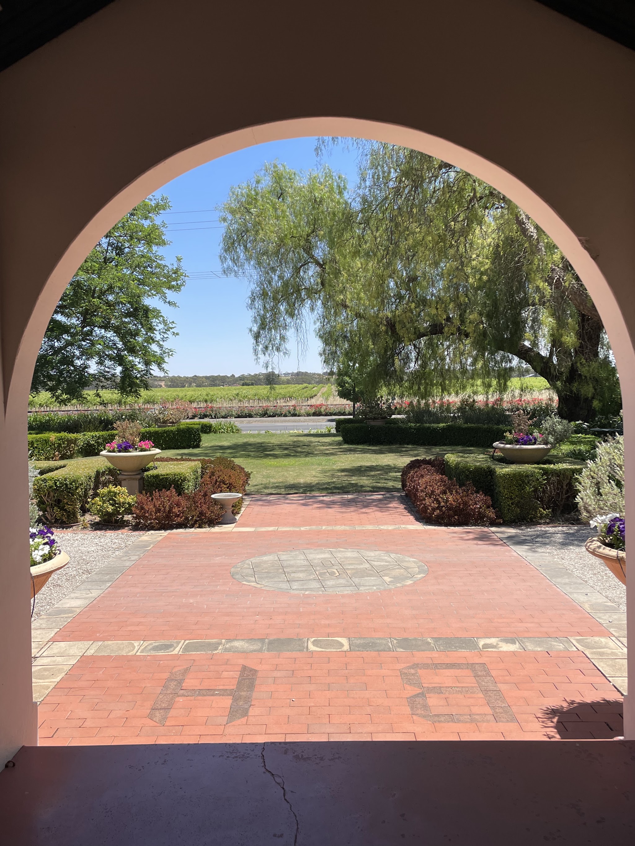 The view out through the entrance arch by day: a weeping willow, the formal garden and the vineyard beyond